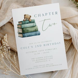 Puede incluir: Una tarjeta de invitación blanca con el texto "Chapter Two" y "Cole's 2nd Birthday". Presenta una pila de libros en tonos verdes y azules, coronada por un pequeño oso de peluche. La tarjeta incluye detalles del evento.