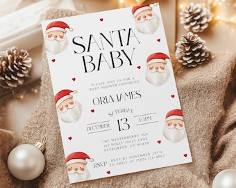May include: A white invitation card with the text "SANTA BABY" and Santa Claus illustrations. The card is for a baby shower honoring Oria James on December 13th at The Winterberry Inn. Red hearts and festive decorations surround the card.