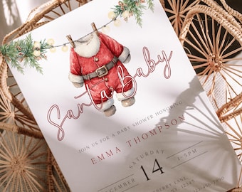 May include: A baby shower invitation with a festive design. It features a watercolour illustration of a Santa Claus outfit hanging on a line, with the words "Santa baby" in cursive script and event details.