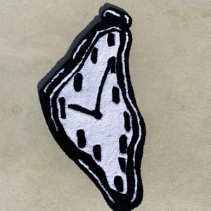 May include: A white and black rug shaped like a melting clock. The clock face has black numbers and a black hand.