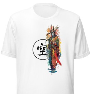 May include: White t-shirt featuring a colourful illustration of a warrior holding a staff. The warrior is surrounded by watercolour-like splashes of colour. The kanji character "空" (meaning "empty") is in a circle in the top left corner of the design.