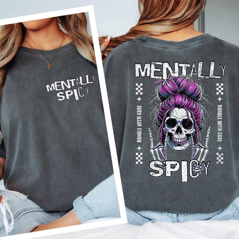 K&ouml;nnte beinhalten: Dunkelgraues Sweatshirt mit dem Text "MENTALLY SPICY" auf der Vorder- und R&uuml;ckseite. Auf der R&uuml;ckseite befindet sich ein Totenkopf mit lila Haaren und einem Dutt sowie die Worte "HANDLE WITH CARE". Das Design ist in Wei&szlig; und Lila gehalten.