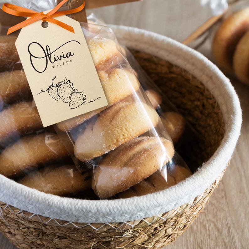 May include: A wicker basket filled with shortbread cookies in a clear plastic bag tied with a brown ribbon and a tag that says "Olivia Wilson" with a drawing of strawberries.