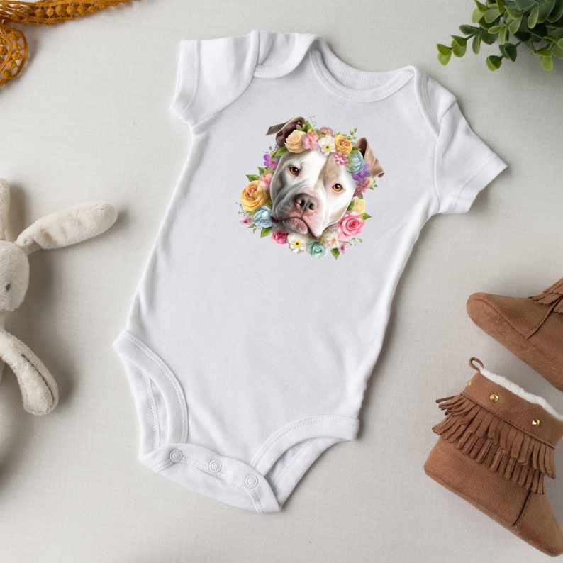 May include: White baby onesie with a colorful floral print featuring a dog wearing a flower crown.