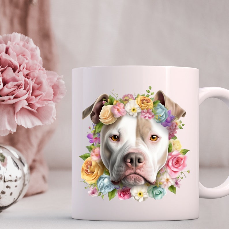 May include: White ceramic mug with a colorful floral wreath around the face of a white and brown pit bull dog. The flowers are pink, yellow, blue, and purple.