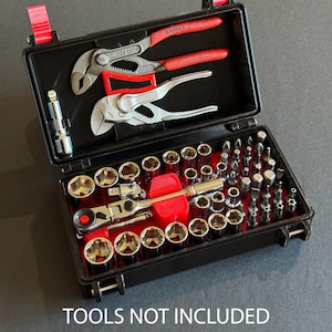 May include: A black toolbox with red accents, open to reveal a set of tools. The set includes pliers, sockets, and bits. The text "TOOLS NOT INCLUDED" is printed at the bottom. The tools are neatly arranged inside the case.