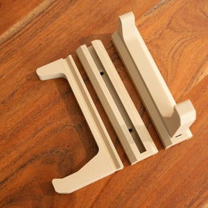 May include: Three beige wooden pieces for a wall-mounted shelf or stand. The pieces are designed to hold a sword or other long object.