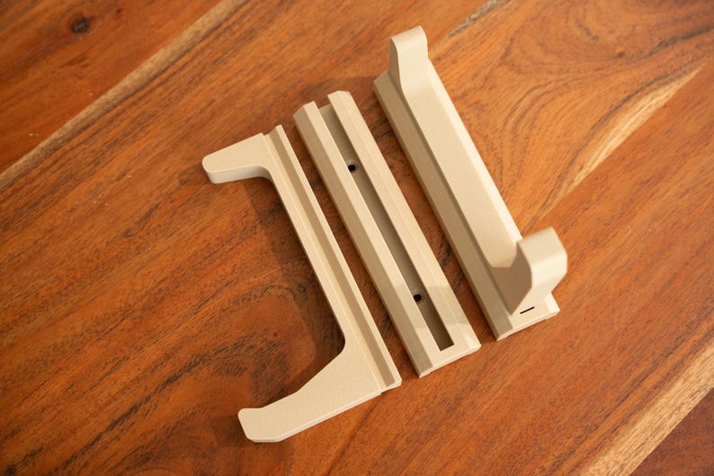 May include: Three beige wooden pieces for a wall-mounted shelf or stand. The pieces are designed to hold a sword or other long object.