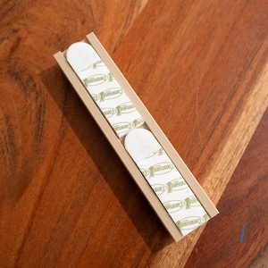 May include: A beige plastic strip with multiple adhesive pads on the back. The pads are white with green text that reads "Premium".