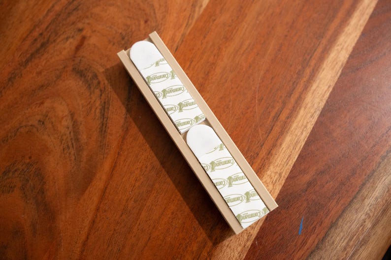 May include: A beige plastic strip with multiple adhesive pads on the back. The pads are white with green text that reads "Premium".