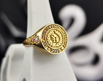 May include: Gold class ring with a red and white stone setting. The ring features the Sam Houston State University logo and the year 2025.
