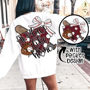 May include: White sweatshirt with a red, white, and black baseball-themed graphic that says "No place like home". The graphic includes a baseball bat, a baseball glove, and a baseball. The sweatshirt has a pocket on the front with a matching graphic.