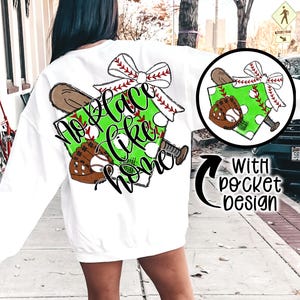 May include: White sweatshirt with a green and white baseball-themed graphic that says "No place like home" with a red bow and a baseball glove. The graphic is also shown on a separate pocket design.