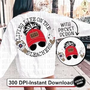 May include: White sweatshirt with a graphic design of a woman with a messy bun wearing a red baseball cap with the word "Mama" on it. The graphic says "Living Life on the Bleachers". The design also includes a drink with a straw and a heart with leopard print. The text "With Pocket Design" is also included.