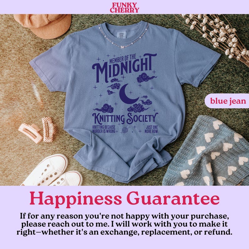 May include: A blue jean colored t-shirt with the text "MEMBER OF THE MIDNIGHT KNITTING SOCIETY" in dark blue. The design includes a crescent moon, clouds, and stars. The shirt is surrounded by accessories.