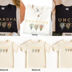 May include: A collection of t-shirts in various colors, including black and natural, each featuring a floral design and a family-related word such as "Grandpa," "Grandma," "Uncle," "Sister," "Cousin," and "Brother."