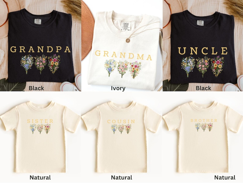 May include: A collection of t-shirts in various colors, including black and natural, each featuring a floral design and a family-related word such as "Grandpa," "Grandma," "Uncle," "Sister," "Cousin," and "Brother."