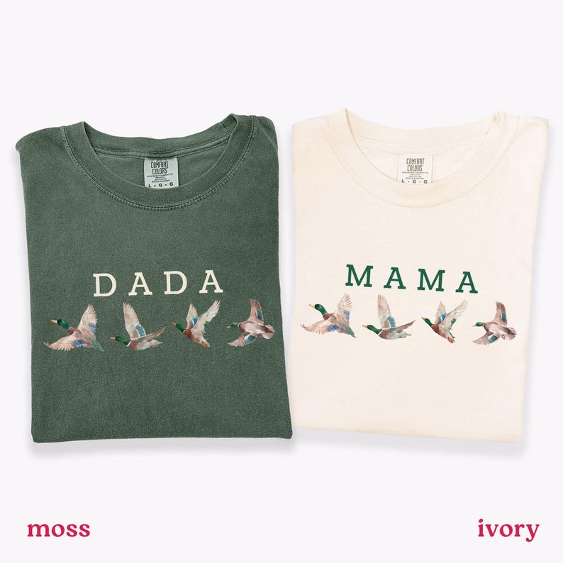 Peut inclure: Deux t-shirts pli&eacute;s, l'un vert mousse et l'autre ivoire. Le t-shirt vert mousse porte l'inscription "DADA" avec des canards brod&eacute;s. Le t-shirt ivoire porte l'inscription "MAMA" avec des canards brod&eacute;s.