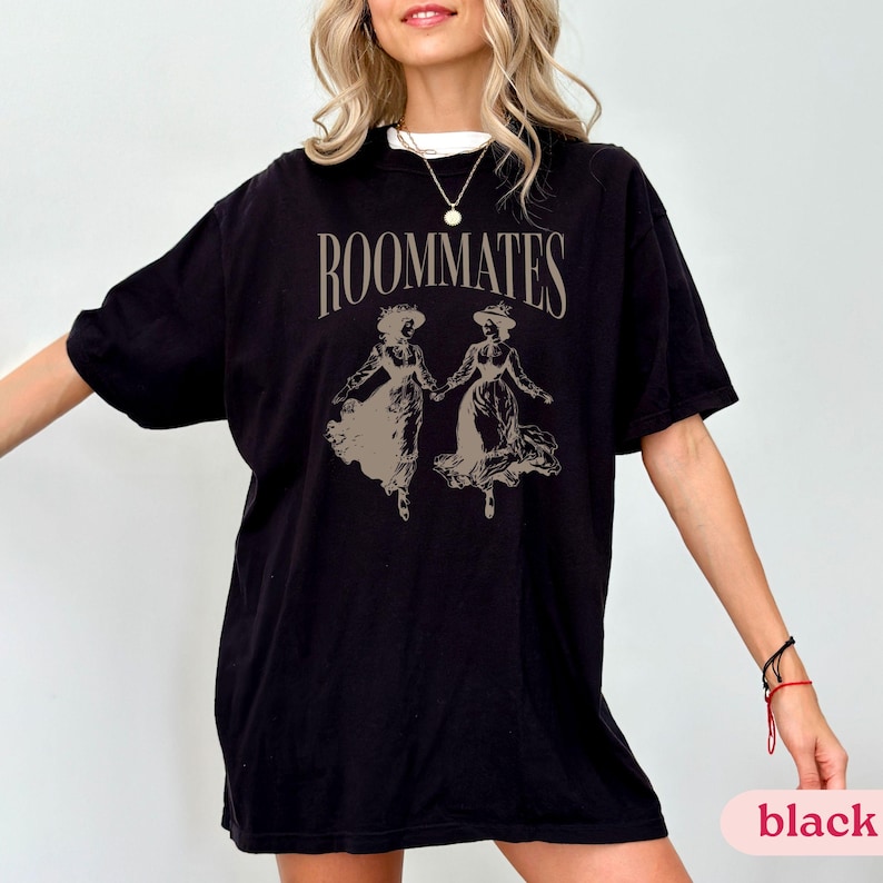 May include: Black oversized t-shirt with a graphic print of two women in dresses and the text "ROOMMATES".