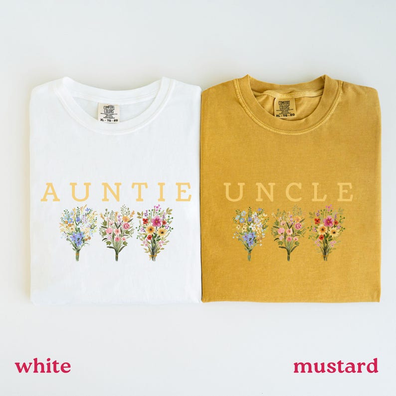 May include: White and mustard-colored t-shirts with the words "AUNTIE" and "UNCLE" printed in gold. Each shirt features a floral bouquet design in pastel colors. The shirts are a Comfort Colors brand.