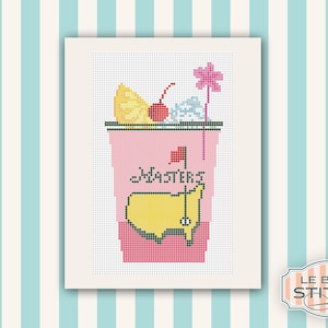 May include: A pink and yellow cross-stitch design of a cocktail glass with a lemon wedge, cherry, and a golf flag. The glass has the word "Masters" written on it.