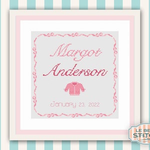 May include: A pink and white cross-stitch pattern with a pink baby sweater, the name "Margot Anderson", and the date "January 23, 2022".