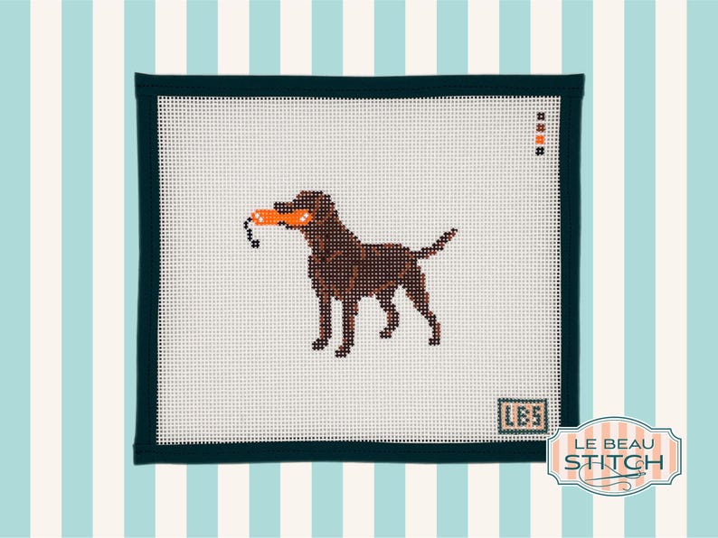 Puede incluir: Un lienzo de punto de aguja con un perro marr&oacute;n sosteniendo un juguete naranja en la boca. El perro est&aacute; cosido sobre un fondo blanco con un borde verde oscuro. El fondo es un patr&oacute;n de rayas azul claro y blanco. El texto "LBS" y "LE BEAU STITCH".