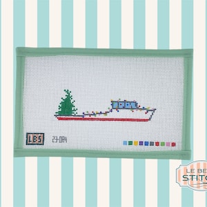 May include: A needlepoint canvas with a white background featuring a boat with a Christmas tree on the bow and colorful lights. The boat is red, white, and blue. The canvas is framed with a light green border. The text "LB5" and "23-004" are in the lower left corner of the canvas.