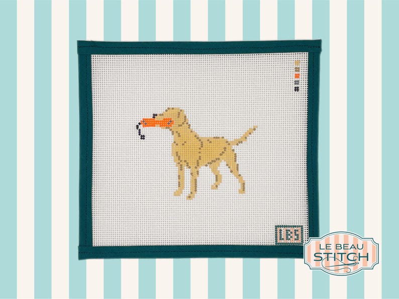Puede incluir: Lienzo de punto de aguja con un Labrador Retriever amarillo sosteniendo un juguete naranja. El perro est&aacute; cosido sobre lienzo blanco, enmarcado por un borde verde oscuro. El dise&ntilde;o incluye el texto "LBS" y el logotipo "Le Beau Stitch".