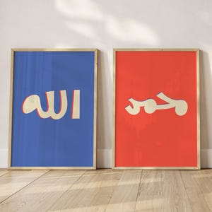May include: Two framed art prints. One features the word "Allah" in cream-colored Arabic script on a blue background. The other print displays the word "Muhammad" in cream-colored Arabic script on a red background. Both are in wooden frames.