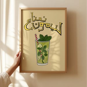 May include: A framed art print featuring a refreshing drink illustration. The artwork depicts a tall glass filled with a green beverage, mint leaves, lime slices, and a red and white striped straw. The text in the image is in a foreign language.
