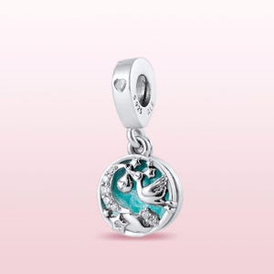 May include: Silver charm with a blue and white enamel design of a stork carrying a baby in a swaddle. The charm has a crescent moon and stars around the stork. The charm is marked with "925 ALE" on the back.