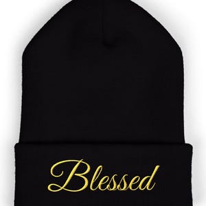 May include: Black beanie with the word "Blessed" embroidered in gold script across the folded brim. The beanie is a classic, close-fitting style, suitable for cold weather. The simple design makes it versatile for various outfits.