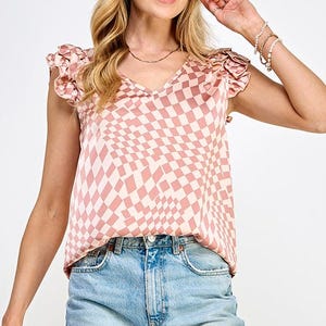 May include: A pink and white checkered top with ruffled sleeves. The top has a v-neck and is made of a silky material.
