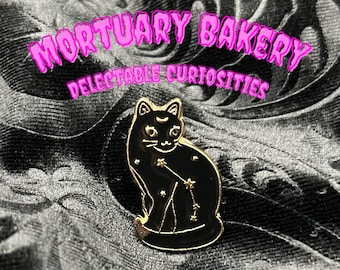 May include: Black enamel pin featuring a black cat with gold stars and a crescent moon. The pin is a part of the "Mortuary Bakery Delectable Curiosities" collection.