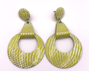 May include: A pair of yellow and silver earrings with a geometric pattern. The earrings are shaped like a circle with a smaller circle cut out of the center.