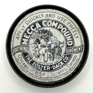 May include: Vintage round tin of Mecca Compound ointment. The label features a black and white illustration of a desert scene with camels and figures. Text includes "Apply Quickly and Use Freely" and "The Foster-Dack Co."