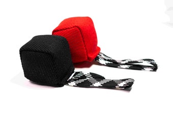 Peut inclure: Deux balles lestées en tissu avec des sangles à motifs noir et blanc. Une balle est rouge et l'autre est noire.