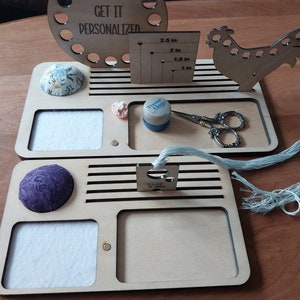 Puede incluir: Organizador de bordado de madera con un porta hilos circular, una regla, un alfiletero, un pequeño recipiente, un par de tijeras y un cortador de hilo. El organizador tiene el texto "GET IT PERSONALIZED".