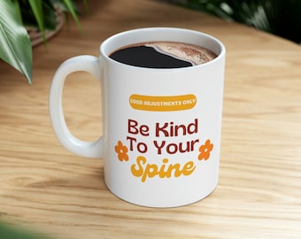 May include: White ceramic coffee mug with a black handle. The mug has a brown and orange graphic that says "Good Adjustments Only Be Kind To Your Spine" with two orange flowers on either side of the text.