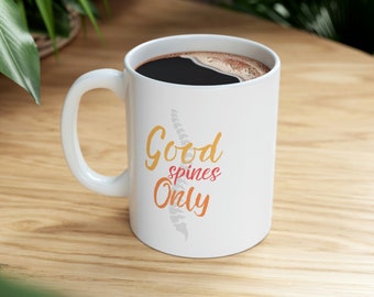 May include: White ceramic coffee mug with a black handle. The mug has a graphic of a spine with the text "Good spines Only" in orange and pink.