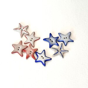 Puede incluir: Un conjunto de botones en forma de estrella de mar, en rojo, blanco y azul. Los botones tienen dos agujeros para coser y están decorados con patrones de puntos. Estos botones decorativos son ideales para proyectos de manualidades.
