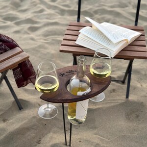 May include: A wooden wine holder with two glass wine glasses and a bottle of wine. The holder is engraved with the words "the millies wine + fun".