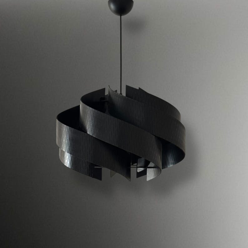 May include: A modern black pendant light with a unique, swirling design. The light fixture is suspended from a black cord and features layered, curved wooden slats. The overall shape is reminiscent of a spiral or a stylized flower.