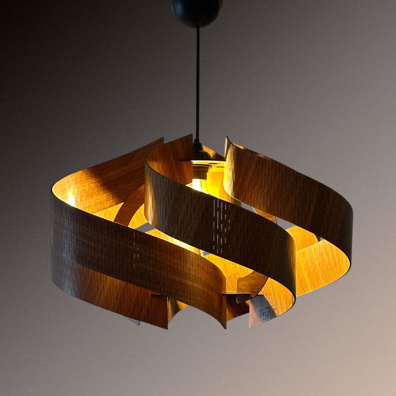 Op de afbeelding: Een moderne hanglamp met een uniek ontwerp. Het heeft gebogen houten lamellen in een spiraalvormige opstelling, die een warme, uitnodigende gloed cre&euml;ren. De lamp hangt aan een zwart snoer en een plafondbevestiging. Ideaal voor binnenverlichting.