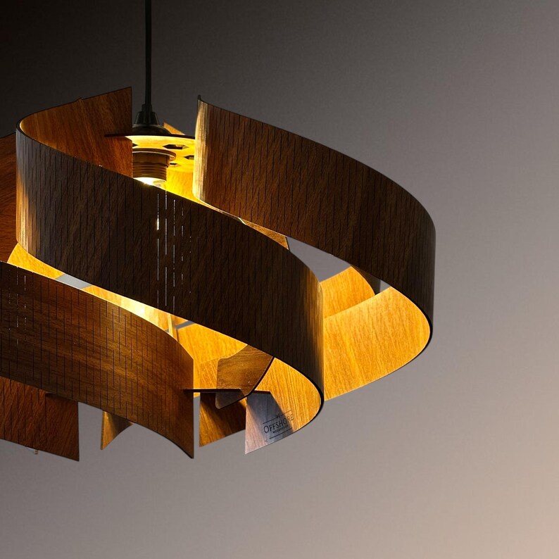 May include: A modern wooden pendant light fixture with a spiral design. The light fixture is made of curved, dark brown wood and has a warm, yellow glow from the lightbulb inside. The fixture hangs from a black cord.