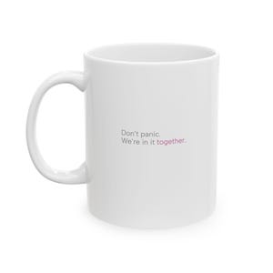 May include: White ceramic mug with the text "Don't panic. We're in it together." in grey and pink lettering.