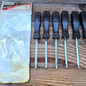 May include: A six-piece Torx and RV screwdriver set with black handles and silver shafts. The set is in a clear plastic package with a white and red label that reads "CE TOOLS". The screwdrivers are arranged on a wooden surface.