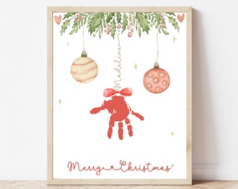 May include: A framed Christmas print featuring a red handprint design with a bow, hanging ornaments, and the text "Merry Christmas." The name "Madeline" is written vertically. The print has a watercolor style with a festive theme.