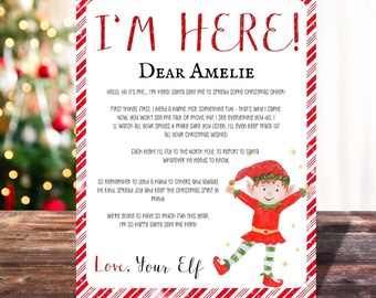 Peut inclure: Une carte rayée rouge et blanche avec le texte "I'm Here!" et "Dear Amelie". La carte représente un lutin de dessin animé avec un chapeau rouge et un pantalon vert. Le texte sur la carte dit : "Hello, Hi it's me... I'm here! Santa sent me to spread some Christmas cheer! First things first, I need a name, pick something fun - that's why I came. Now, you won't see me talk or move, but I see everything you do. I'll watch all your smiles & make sure you listen. I'll even keep track of all your Christmas wishes! Each night I'll fly to the North Pole, to report to Santa whatever he needs to know. So remember to lend a hand to others and always be kind, spread joy and keep the Christmas spirit in mind! We're going to have so much fun this year, I'm so happy Santa sent me here! Love, Your Elf"